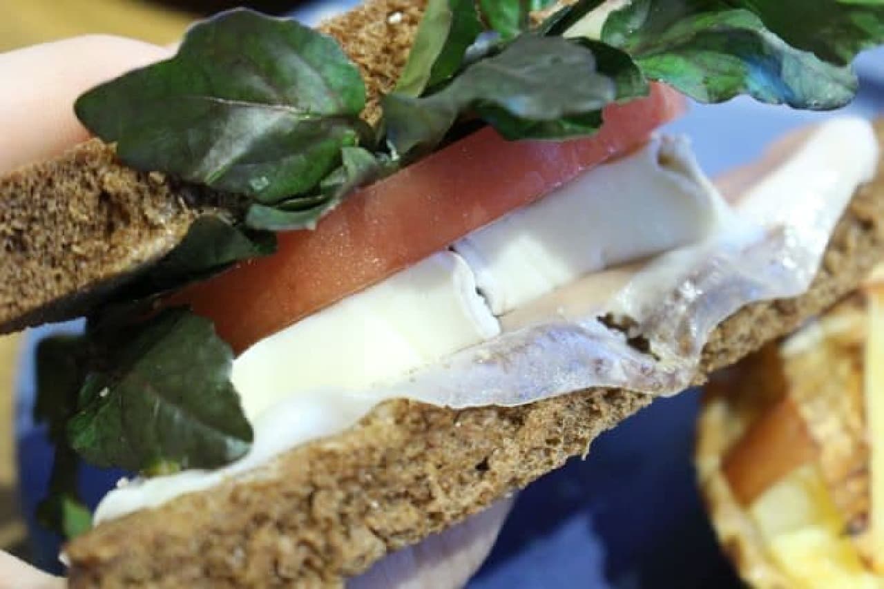 Smooth cheese and prosciutto sandwich is a sandwich of black bread with watercress, camembert, cheese, prosciutto, etc.